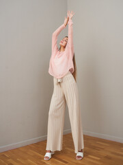 Fototapeta premium Young woman poses in stylish clothing in bright indoor setting