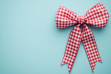 a red gingham plaid ribbon bow tied vector on soft light blue background, clean and minimalistic banner design with space. Festive/Holiday Decoration.