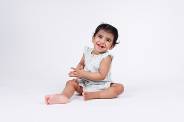 Cute happy little baby girl looking at camera with expression of joy and happiness wearing white dress isolated on white background