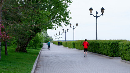 Men running on a spring morning on a park alley in the city. Healthy Lifestyle.