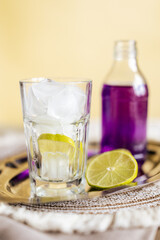 Refreshing lime tonic with vibrant purple soda in a glass with ice, creating a striking contrast...