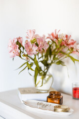 A bouquet of Alstroemeria flowers in a glass vase, accompanied by a book and elegant accessories. Ideal for concepts of beauty, home decor, and refined aesthetics