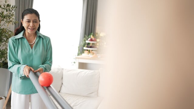 Grandmother holding pipe and carrying ball rolling game for exercise to improve eye, hand coordination or enhance focus and concentration. Elder couple providing stress relieve. Healthcare. Myrmidon.