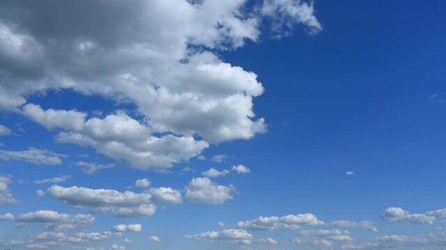 Cumulus clouds slowly drift across the blue sky