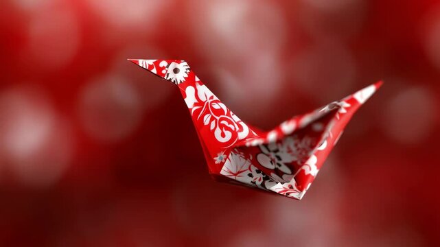 Red origami crane in flight against a blurred red background. Intricate floral pattern.