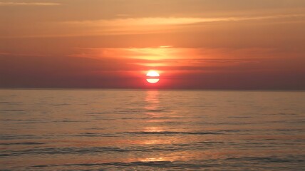 Obraz premium A serene sunset over the ocean with a vibrant orange sky and reflections on the water surface view scene