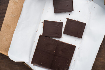 Closeup photo of unwrapped Chocolate bar on wooden table.