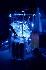 A garland in a glass vase. The design of a night lamp. A beautiful blue glow.