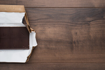 Top view photo of unwrapped Chocolate bar on wooden table with copy space left side composition.
