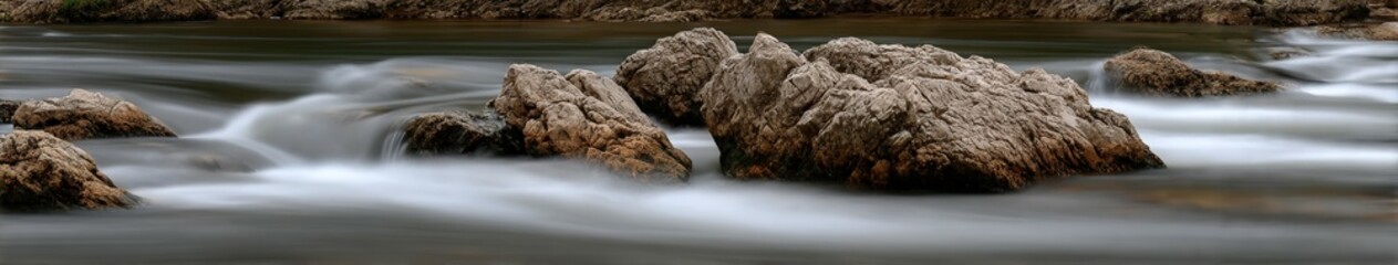 Smooth flowing water rushes around large rocks in mountain river
