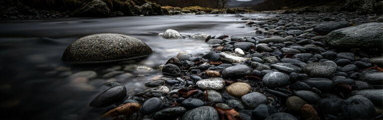 Obraz premium Still river flows over rocky shoreline in late afternoon