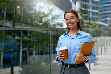 Happy businesswoman holding tablet and coffee outdoors