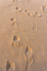 Multiple Human Footprints on Soft Golden Desert Sand at Sunset with Wind-Sculpted Patterns and a Sense of Solitude and Adventure