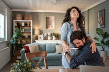 Happy couple celebrating positive pregnancy test at home