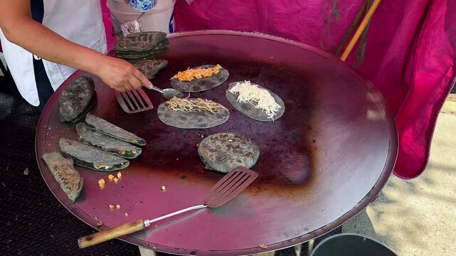 Street food vendor cooks Quesadillas and Tlacoyos made with fresh blue corn tortillas in Mexico City, Mexico.