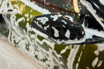 A luxury car is undergoing a foam wash treatment to enhance its appearance and shine