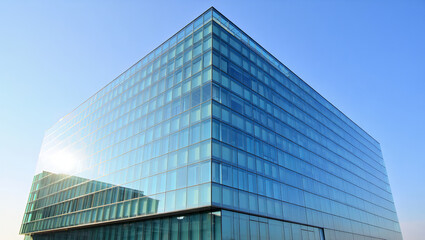 Obraz premium Modern Glass Office Building with Reflective Facade under Bright Blue Sky and Sunlight