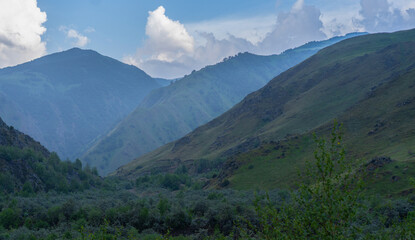 Naklejka premium Beautiful mountain landscape with lush green valley and misty peaks during daytime