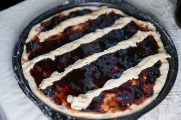 Homemade dessert preparation with a jam-filled pastry on a baking tray in a cozy kitchen setting