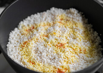 Cooking saffron-infused rice in a black pot over a stovetop during a culinary session at home