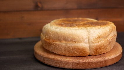 Freshly baked round bread resting on a wooden board in a cozy kitchen setting