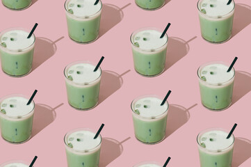 Creative summer pattern made of iced matcha latte on pastel pink background. Minimal healthy matcha latte concept. Trendy drink idea.