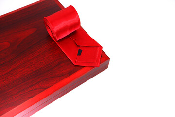 Red tie rolled on wooden frame closeup shot on white background 