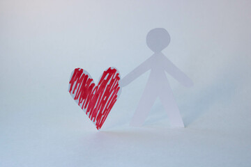 A lone paper man holds a red paper heart. The concept of love, Family Day, Mother's Day, Valentine's Day, March 8th