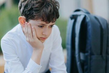 Exhausted Schoolboy Sitting Alone and Looking Away After a Long School Day