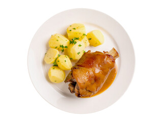 Pork knuckle in a roasting sauce, new potatoes cooked whole and fresh herbs. Top view.