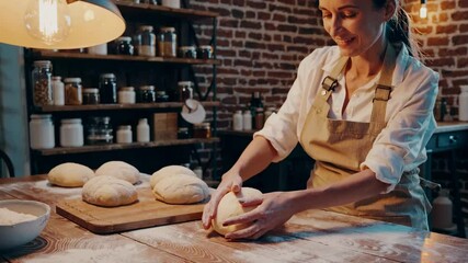 Artisan baker kneading dough in cozy rustic kitchen with brick walls and warm lighting