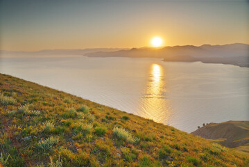 Beautiful spring nature and sea landscape of green grass on cliff during the sunset.