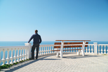Man standing on balcony and look on the sea horizon at day.