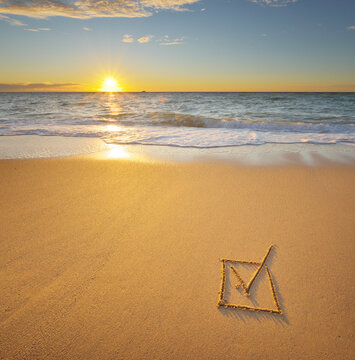 Fototapeta Check mark symbol in box on the beach shore during the sunset.