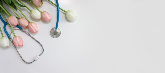 Medical stethoscope and spring tulips on white background. Doctor's or Nurse's Day banner. Selective focus, copy space