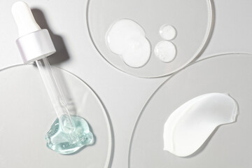Cosmetic cream and milk lotion emulsion and serum set smudge drops swatches with dropper and steel applicator stick spatula on circle transparent plastic background