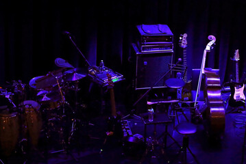 Various musical instruments placed on the stage of a dimly lit live music venue before the show begins