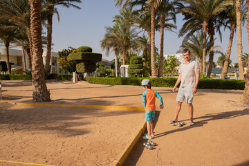 Man and boy playing petanque in hot country, father and son in hotel playing on sand