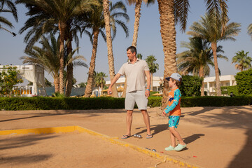 Man and boy playing petanque in hot country, father and son in hotel playing on sand