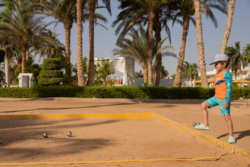 Man and boy playing petanque in hot country, father and son in hotel playing on sand