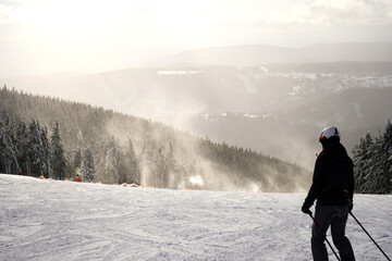 Woman in ski gear gliding through a snowy forest shrouded in mist. A serene and adventurous winter...