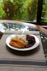 Rice and beans accompanied by a breaded tilapia fillet. Healthy Costa Rican lunch.