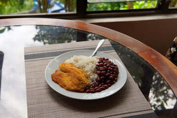 Rice and beans accompanied by a breaded tilapia fillet. Healthy Costa Rican lunch.