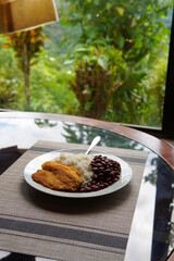 Rice and beans accompanied by a breaded tilapia fillet. Healthy Costa Rican lunch.