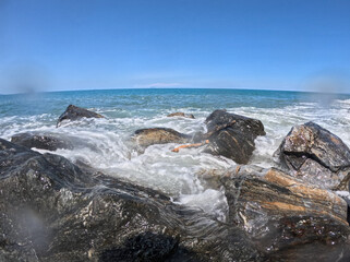 Panorama fish eye of waves of the Mediterranean Sea crashing on the rocks. Photo taken along the Sicilian coast on a beautiful sunny day