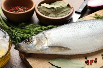 Salted herring, spices and knife on wooden table, closeup