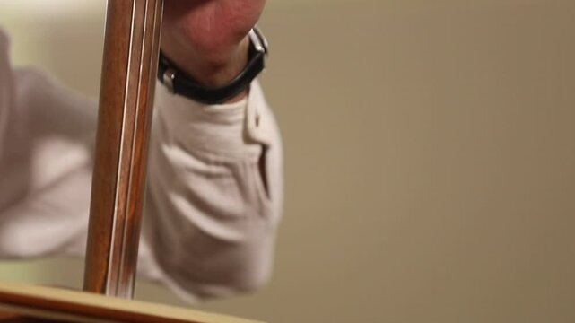 A close-up shot captures a musician's hands skillfully playing a  traditional kamancheh, a spike fiddle, drawing the bow across its strings  in a dynamic and focused musical performance.
