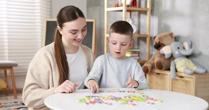 Dyslexia. Mother and her son learning letters at table indoors