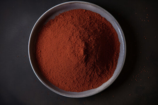 Close up of ground sumac spice on a gray ceramic plate viewed from above