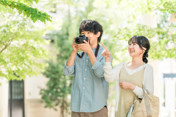 旅行先で一眼レフカメラで写真を撮る男性と女性  © buritora